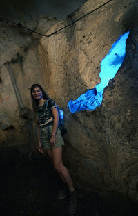 Woman standing by rock formation in cave
