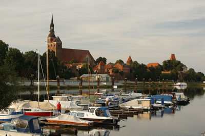 Boats moored at harbor against buildings in city