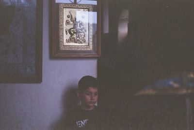 Portrait of young man looking through window at home