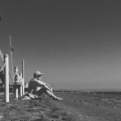 People sitting on field against clear sky