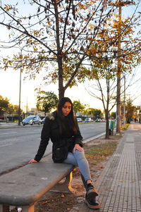 Portrait of young woman sitting on road in city