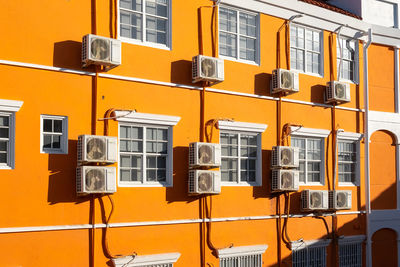 Orange house wall with some air conditioners 