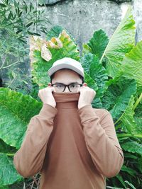 Portrait of young man standing by leaves