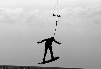 Silhouette skateboarding against the sky