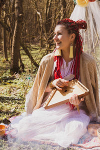 Young woman smiling while sitting on tree