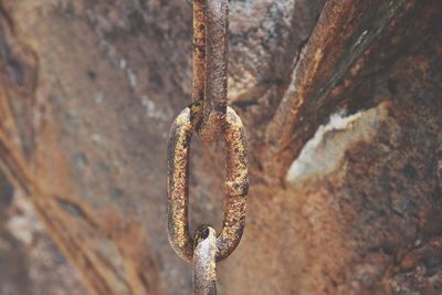 Close-up of rusty chain against wall