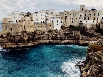 Buildings by sea against sky in city