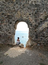 Rear view of man standing by sea against sky