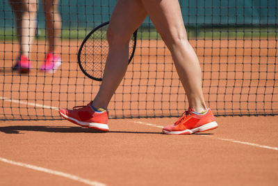 Low section of woman walking on tennis court