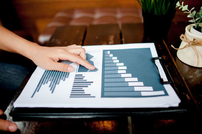 Cropped hand of person analyzing graph on table