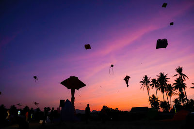 Silhouette kites flying against sky during sunset