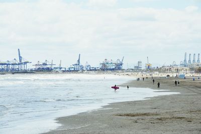 People on pier at beach against sky