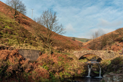 A waterfall and packhorse stone bridge at three shires head in the peak district national park.