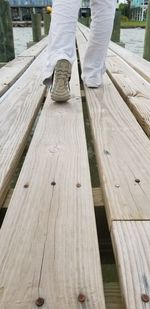 Low section of man standing on wooden plank