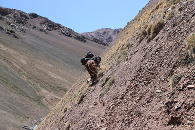 Full length of person on rock in mountains against clear sky