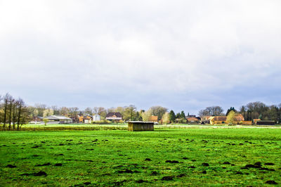 View of grassy field against cloudy sky