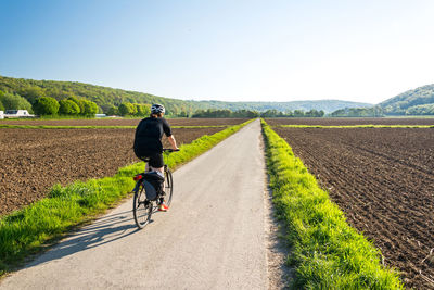 Rear view of man riding bicycle on road