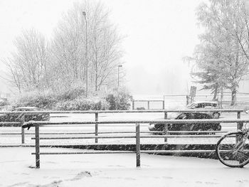 Park bench by snow covered field during winter