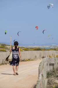 Full length of woman flying at beach against clear sky