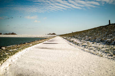 Surface level of road by sea against sky