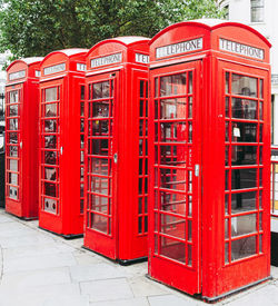 Red telephone booth on sidewalk in city