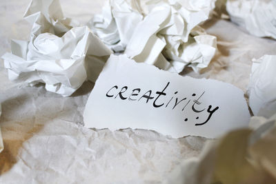 High angle view of creativity text by crumpled paper on table