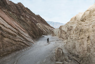 Woman standing amidst mountains against sky