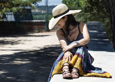 Woman wearing hat sitting outdoors