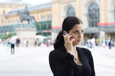 Close-up of beautiful young woman talking on mobile phone at street