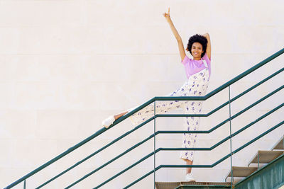 Low angle view of young woman standing against wall