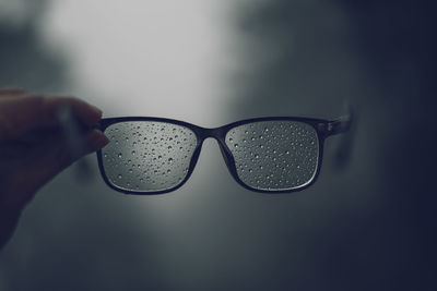 Close-up of hand holding wet eyeglasses