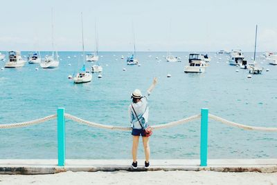 Woman gesturing peace sign at beach against sky