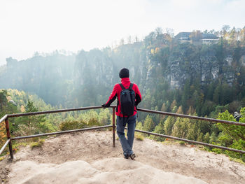 Woman hiker with black backpack on view point and shouting into vally.  bastei bridge, saxony park.