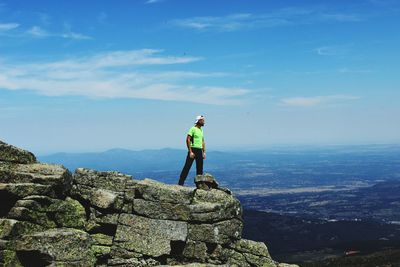 Man standing on rock against sky