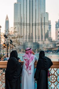 Rear view of woman standing against buildings in city