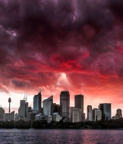 Sea by buildings against sky during sunset