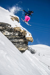 Person paragliding over snowcapped mountain against sky