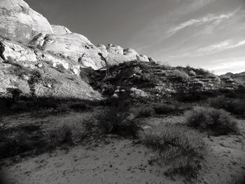 Close-up of sand by mountain against sky