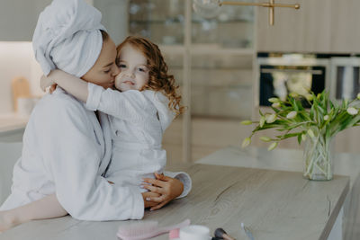 Smiling mother with daughter embracing at home