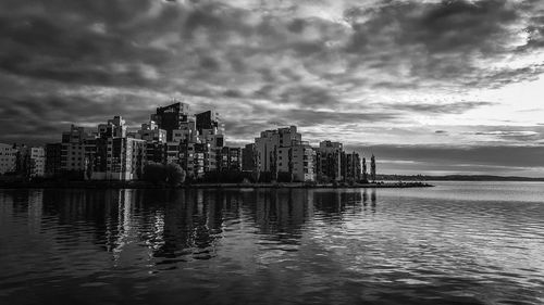 Sea and buildings in city against sky