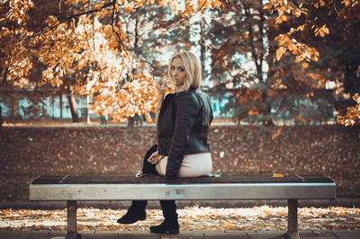 Portrait of beautiful woman sitting on bench at park