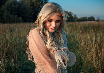 Beautiful young woman standing against field