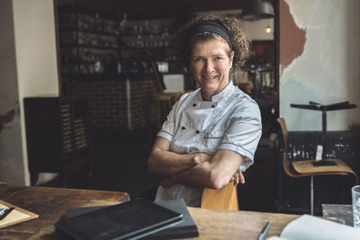 Portrait of smiling mature chef with arms crossed in restaurant