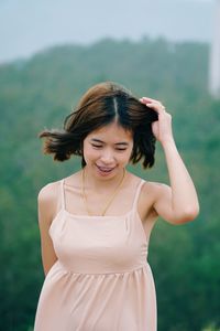 Smiling young woman standing against blurred background