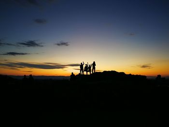 Silhouette people on landscape against sky during sunset