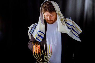 Portrait of young man standing against black background