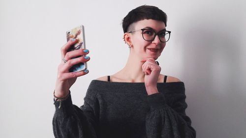 Portrait of young woman using mobile phone against white background