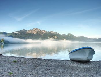 Modern sport fishing paddle boat anchored on shore of the lake bay. peaceful level of lake. 