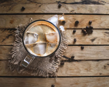 Close-up of ice coffee in a glass on wooden background, top view, copy space