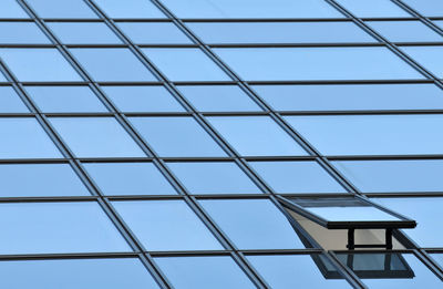 Low angle view of glass building against blue sky